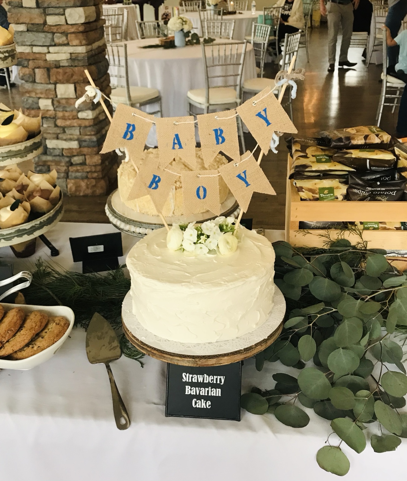 White baby shower cake with blue Baby Boy bunting and white flowers