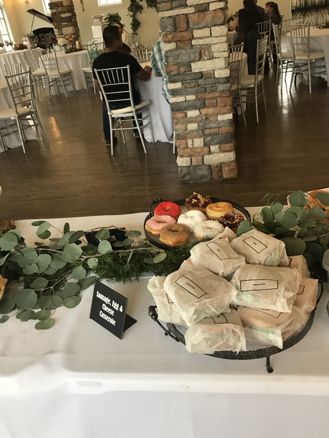 Baby shower brunch display with greenery, pastries and labeled foods
