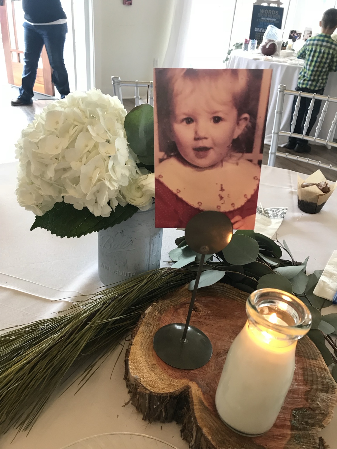 Baby photo centerpiece with white hydrangeas, eucalyptus and a candle