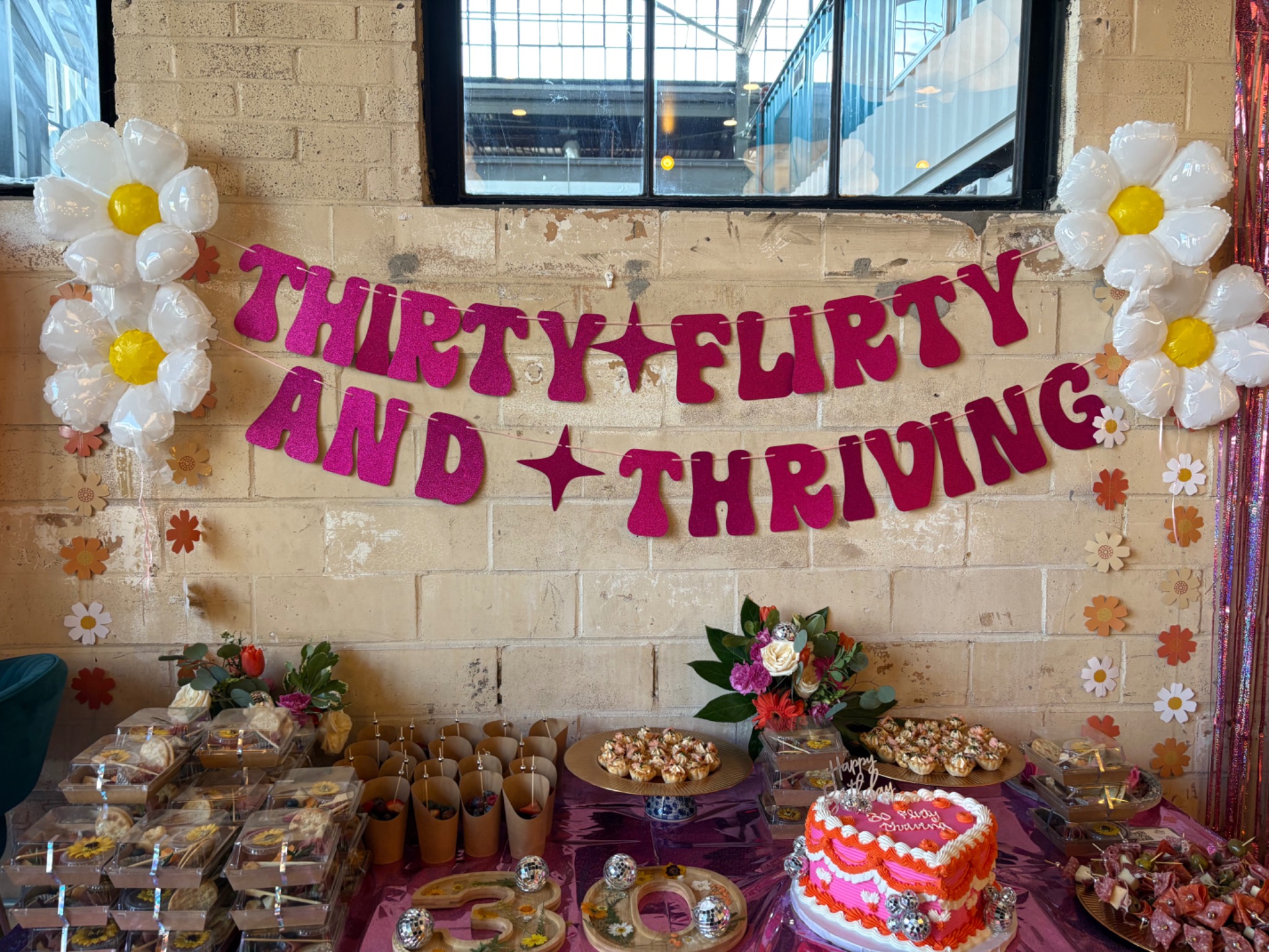 Close view of a thirtieth birthday cake and dessert display with balloon flowers