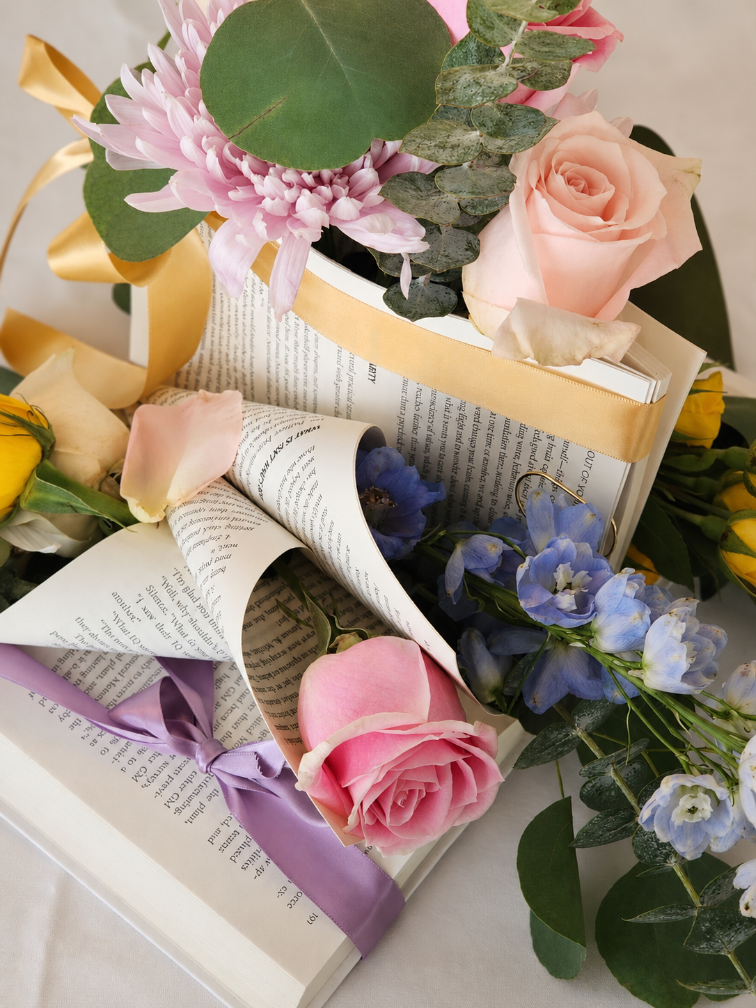 Close-up of flowers, ribbon and folded book pages